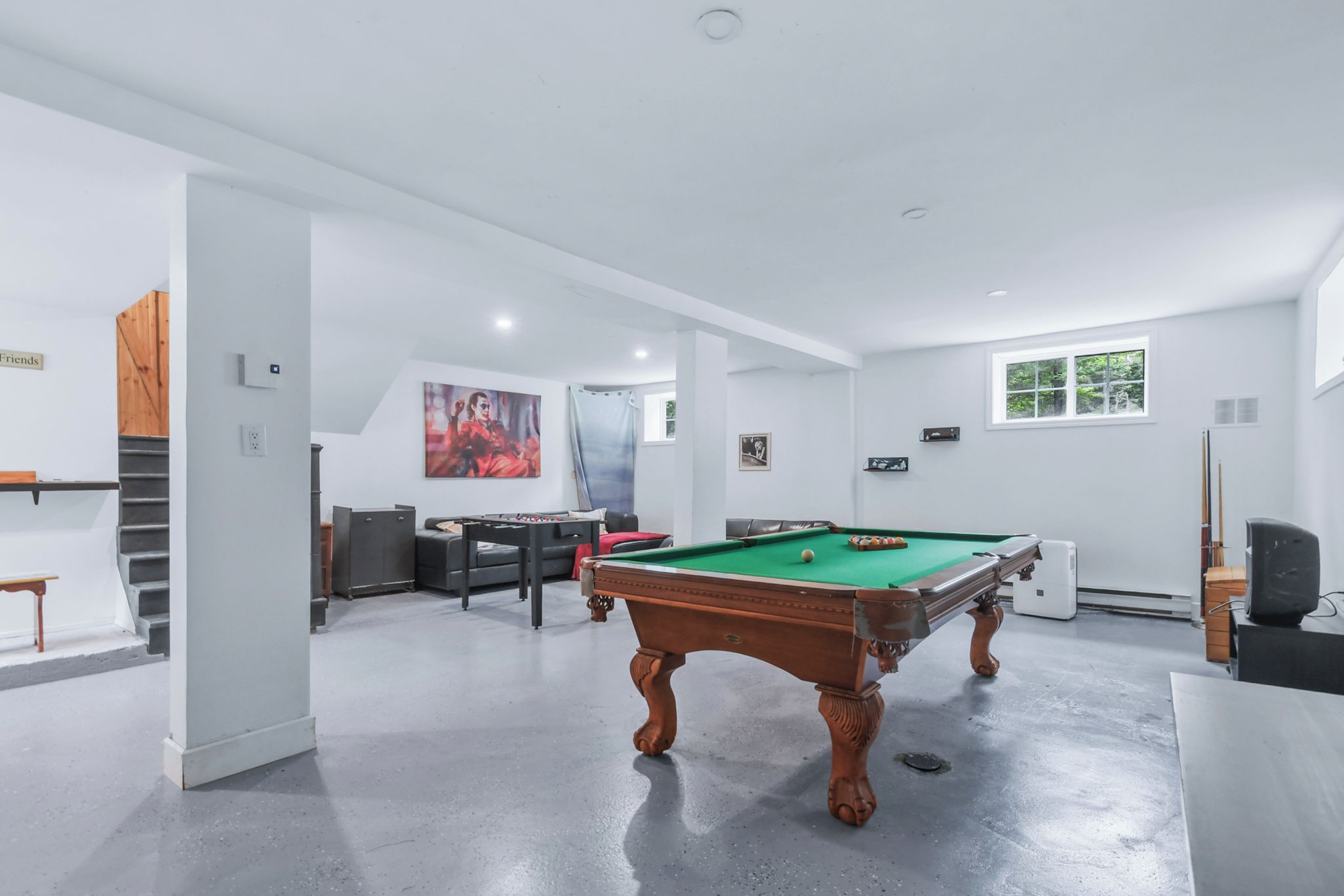 Une pièce spacieuse avec une table de billard, un canapé et un tableau au mur.