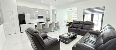 Una sala de estar moderna con un sofá seccional, un sillón reclinable y una mesa de centro.