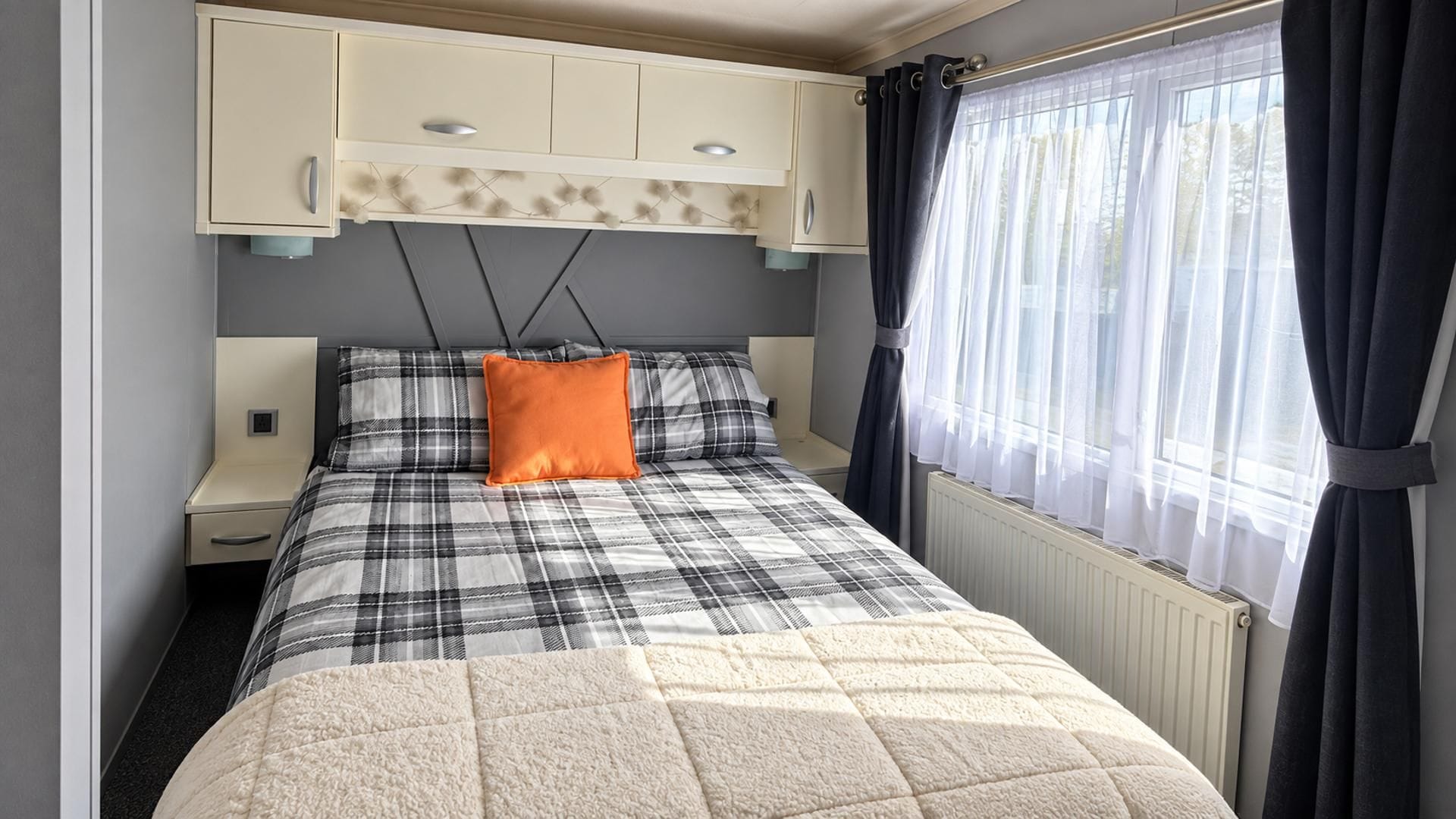 A bedroom with a bed, a nightstand, a wardrobe, and a window with curtains.