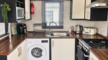 Cocina compacta con lavadora, microondas, tostadora y cocina a gas.
