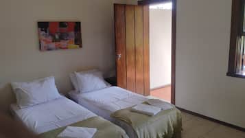 Una habitación con dos camas, una puerta de madera, un cuadro en la pared y una ventana.