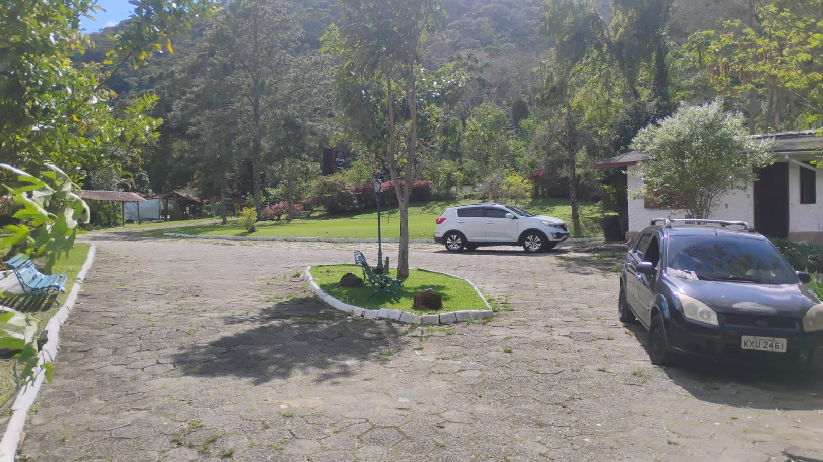 Un camino de entrada pavimentado que conduce a un edificio con coches estacionados.