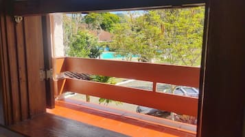 Un balcón con vista a una piscina y coches aparcados.