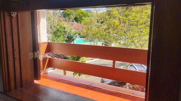 A balcony with a view of a swimming pool and parked cars. - HOTEL ESTÂNCIA DA SERRA (Nova Friburgo)
