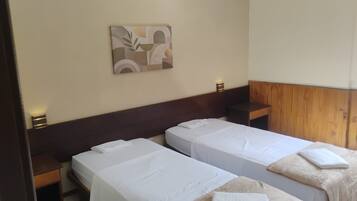 Une chambre d’hôtel avec deux lits simples, une tête de lit en bois, une œuvre d’art accrochée au mur et des lampes de chevet.