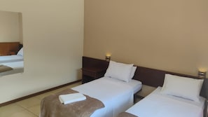 A hotel room with two single beds, a wooden headboard, a nightstand, and a mirror on the wall. - HOTEL ESTÂNCIA DA SERRA (Nova Friburgo)