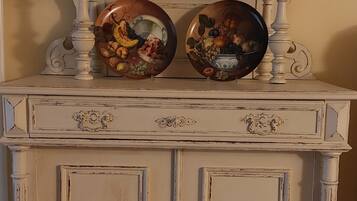 A white cabinet with two decorative plates on top, a wall sign reading 'Cuisine,' and a door with a handle.