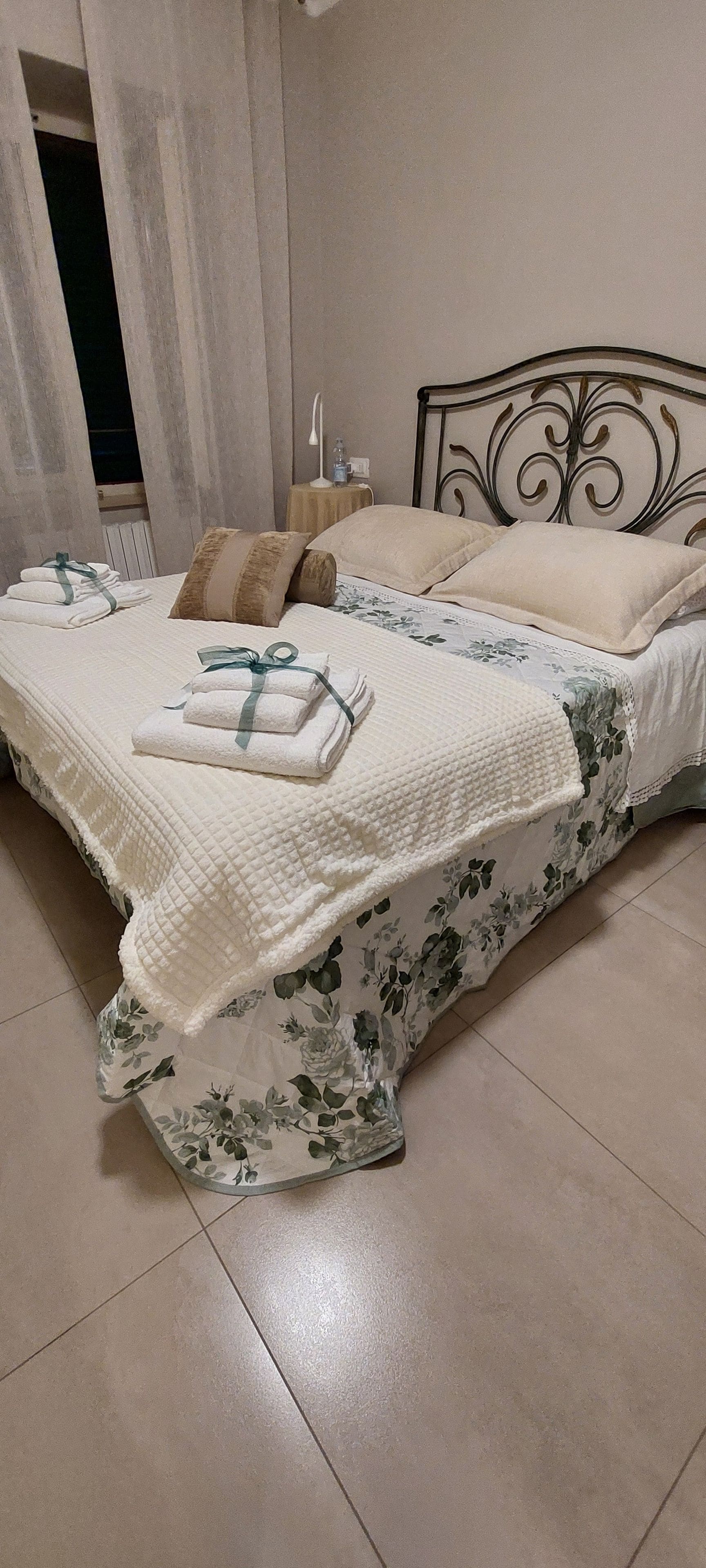 Un letto con una coperta floreale, cuscini e asciugamani piegati.