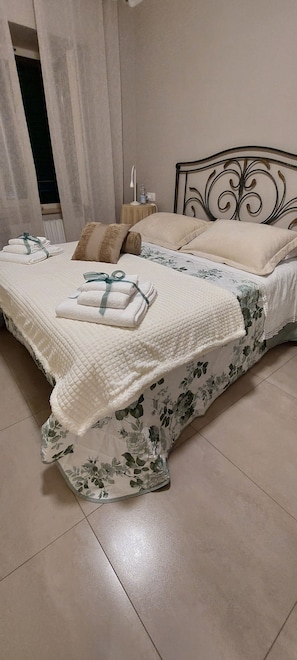 Un lit avec une couvre-lit à motifs floraux, des oreillers et des serviettes pliées.