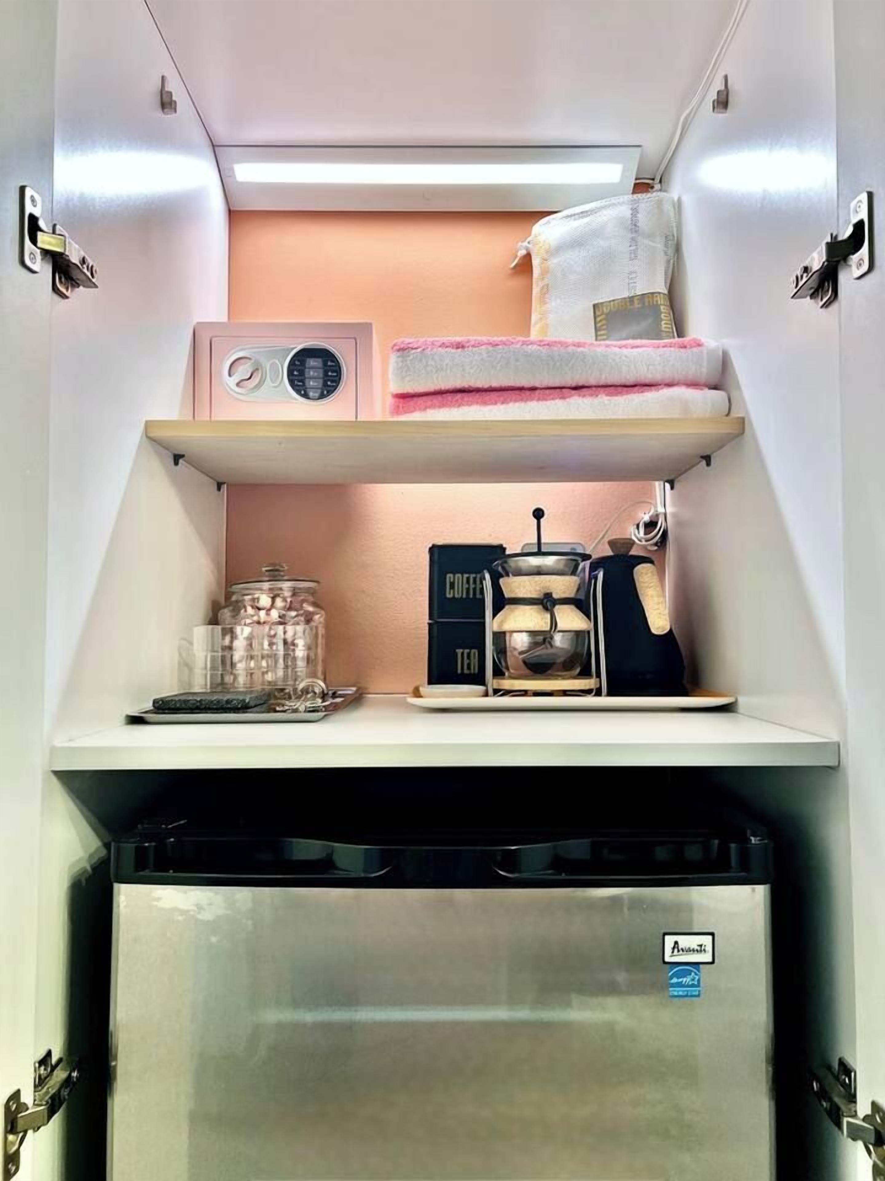 A compact kitchenette with a coffee maker, tea maker, and a small refrigerator.