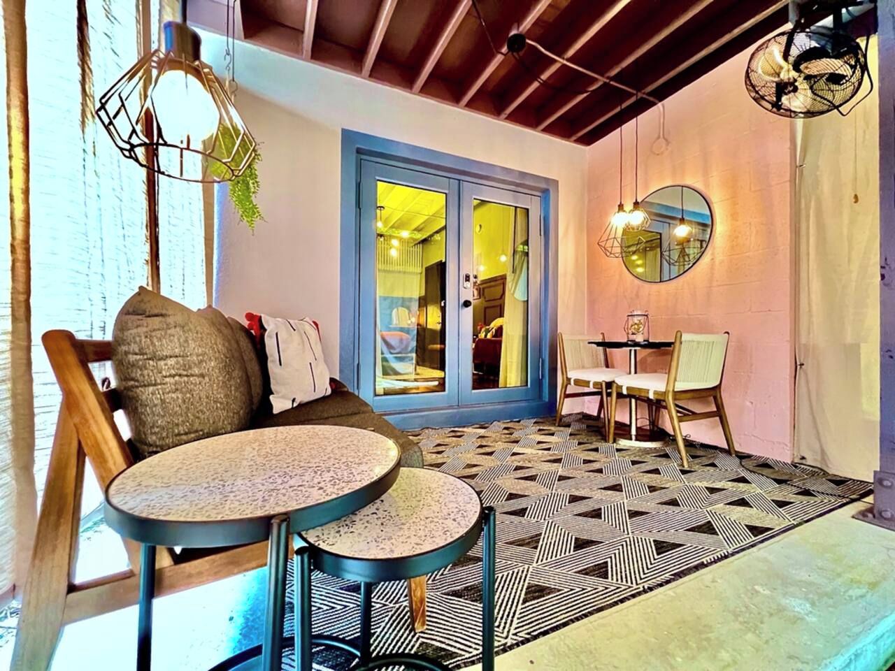 Una habitación con piso estampado, un sofá, dos mesas redondas y una puerta que da a otra estancia.