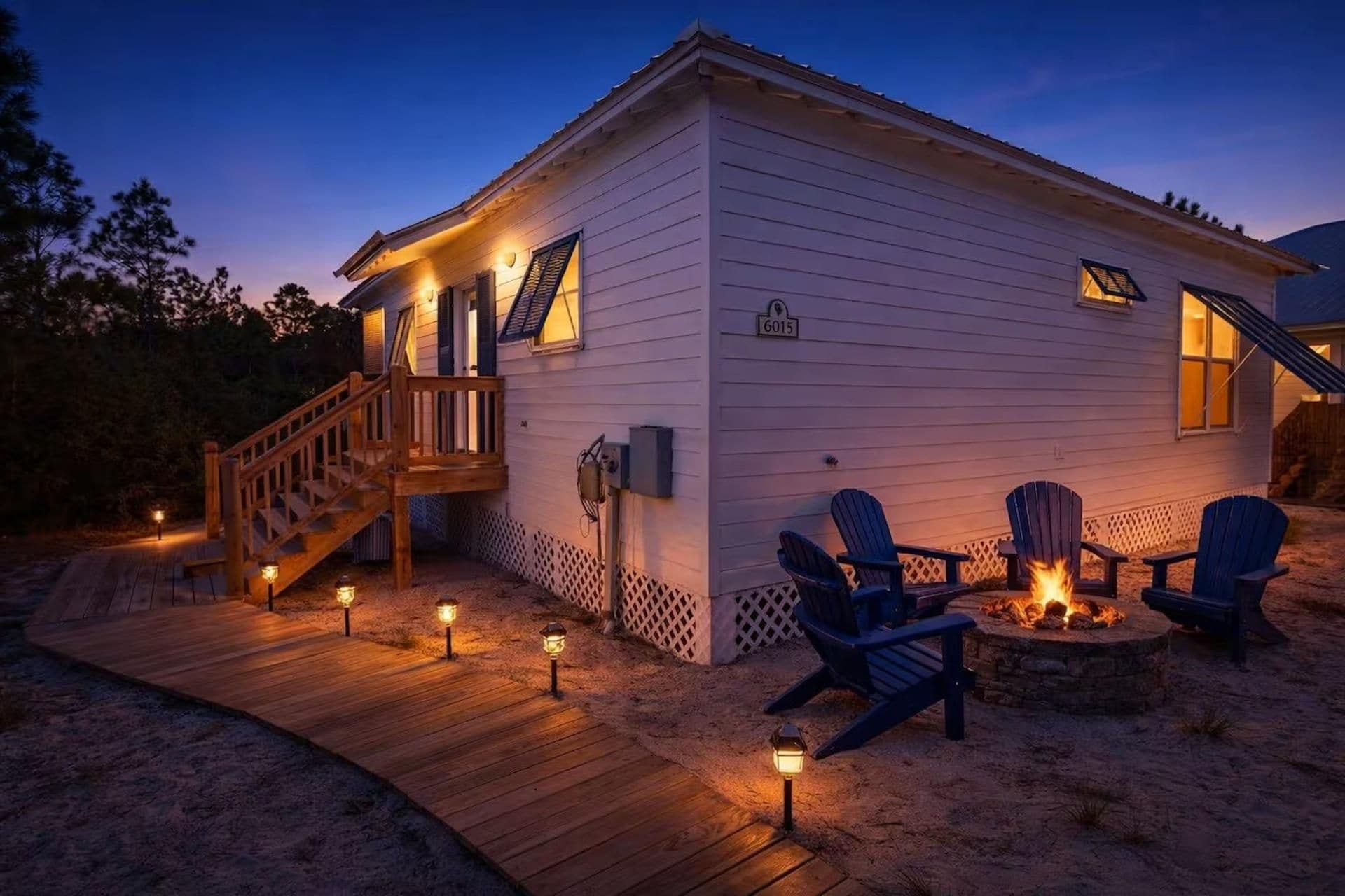 A two-story house with a wooden deck, outdoor seating, and a fire pit.