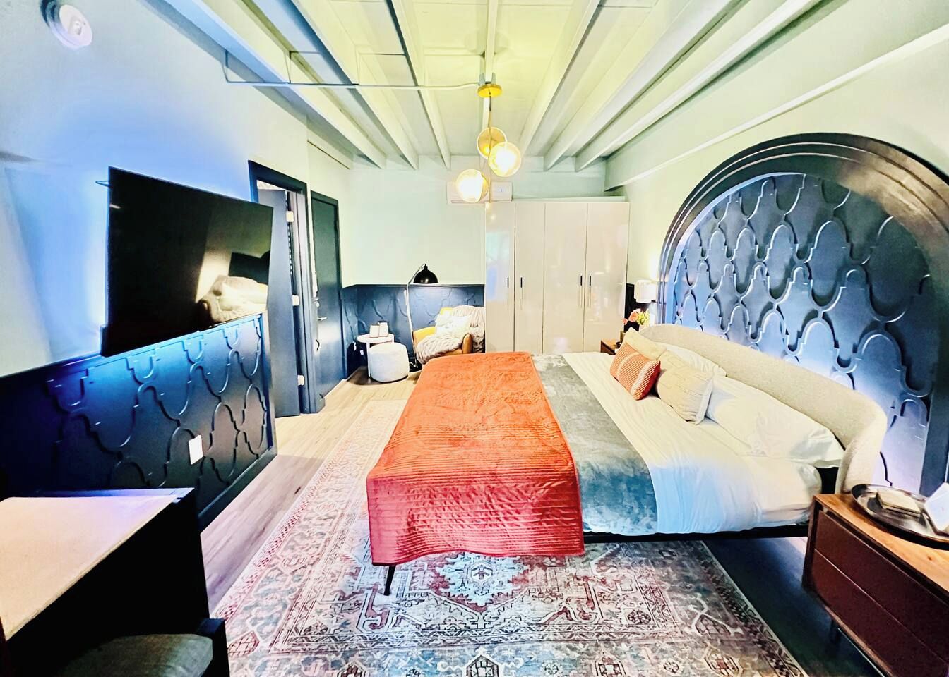Een slaapkamer met een bed, bureau, kledingkast en spiegel.