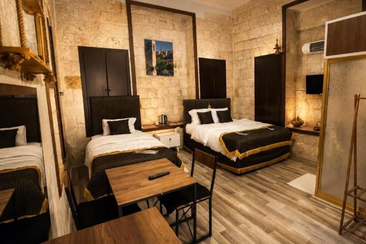 Habitación de hotel con dos camas, una mesa de madera y un armario.