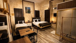 Habitación de hotel con dos camas, una mesa de madera y un armario.