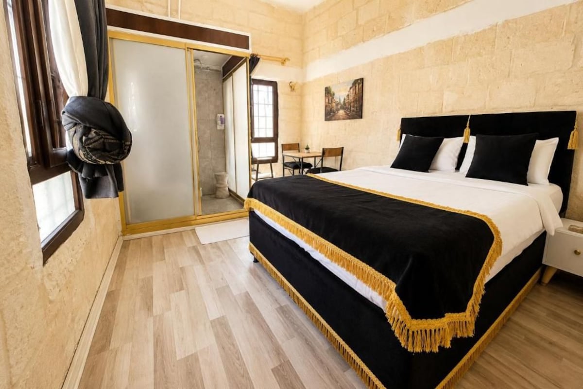 Un dormitorio con una cama grande, suelo de madera, una puerta corredera y un cuadro en la pared.