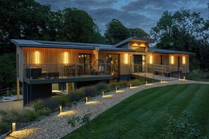 A modern two-story house with a deck, large windows, and a well-maintained lawn. - Hyggee House - Stunning Home in a spectacular setting (Calne)