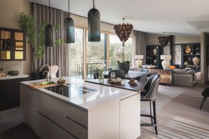 A modern kitchen with an island, pendant lights, and a view to the outdoors. - Hyggee House - Stunning Home in a spectacular setting (Calne)