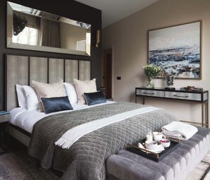 A modern bedroom with a large bed, bedside tables, a bedside mirror, a painting, and a tray with breakfast items. - Hyggee House - Stunning Home in a spectacular setting (Calne)