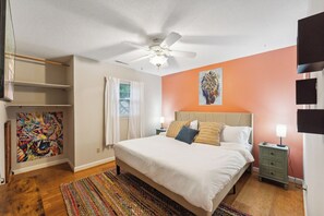A bedroom with a bed, a ceiling fan, a nightstand, a painting, and a window with curtains. - Spacious 4-bedroom house in charming Durham with private pool and game room (Durham)