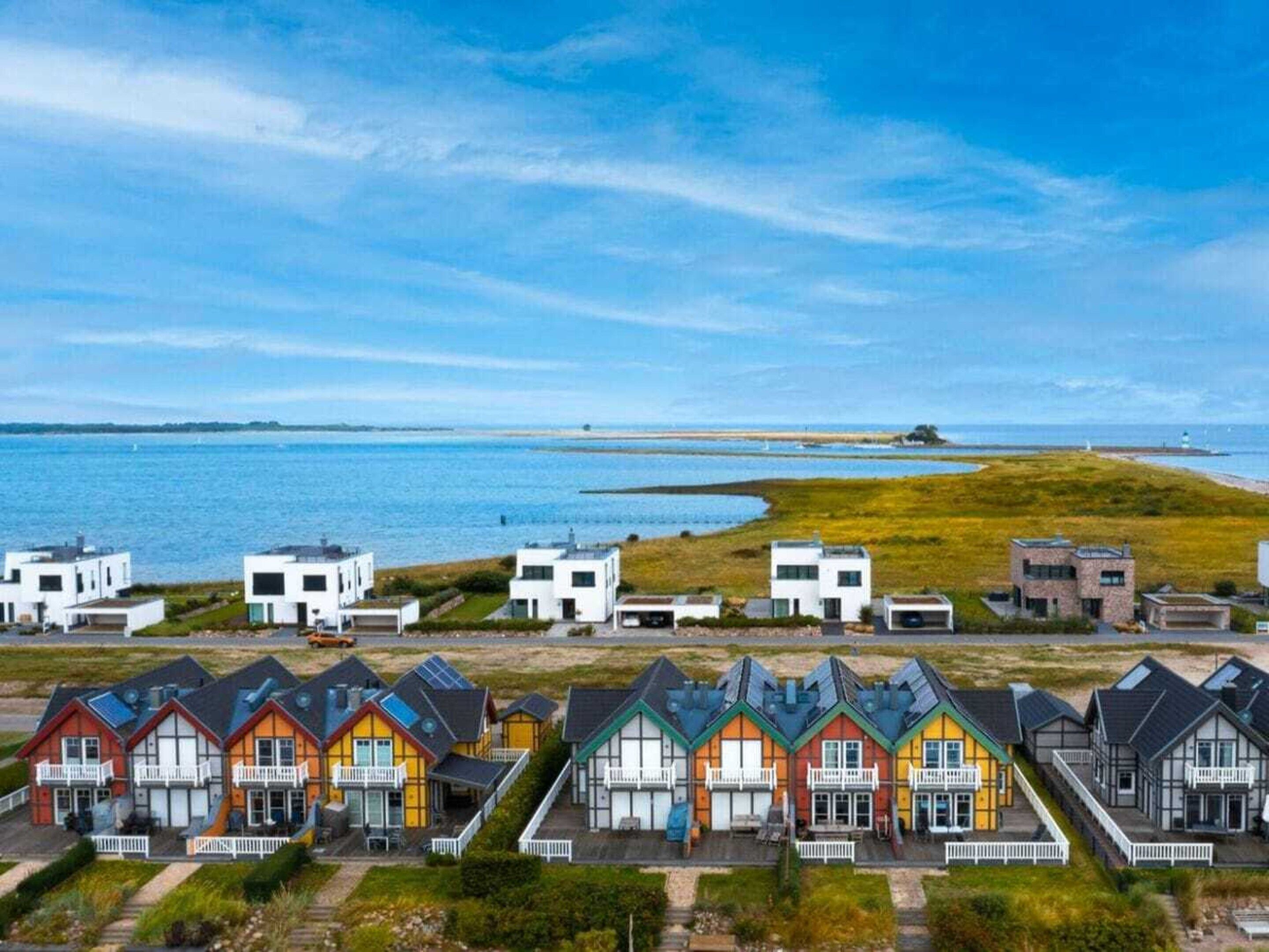 Et kystnære boligområde med moderne huse, en klar himmel og havudsigt.