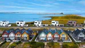Ein Küstenwohngebiet mit modernen Häusern, blauem Himmel und Blick auf das Meer.