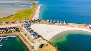 Ein Luftbild eines Küsteneigentums mit Strandzugang, einer Marina und einer Reihe von Häusern.
