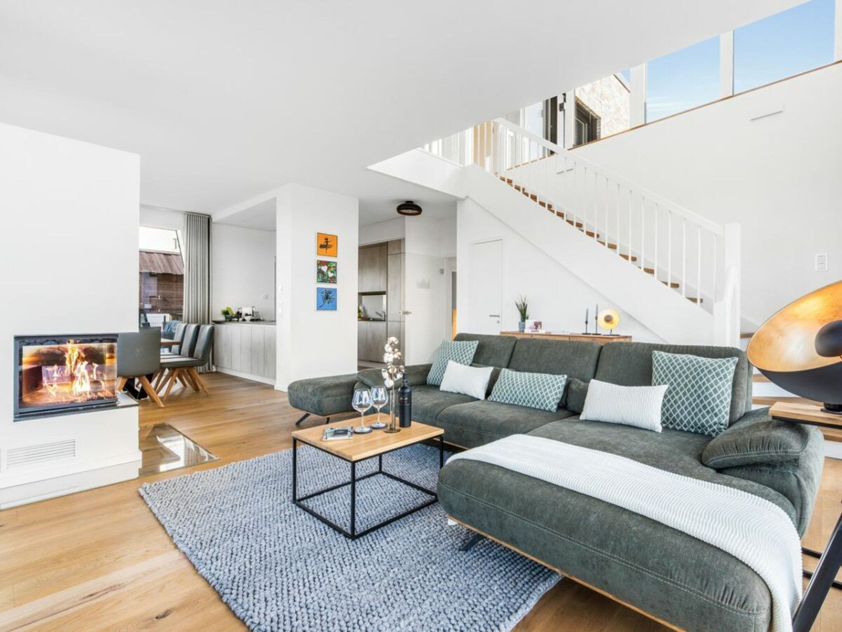 A modern living room with a fireplace, a sofa set, a coffee table, and a staircase leading to an upper floor.
