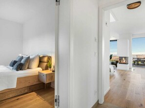 Un dormitorio moderno con una cama de madera, una mesita de noche y vistas a un balcón con chimenea.