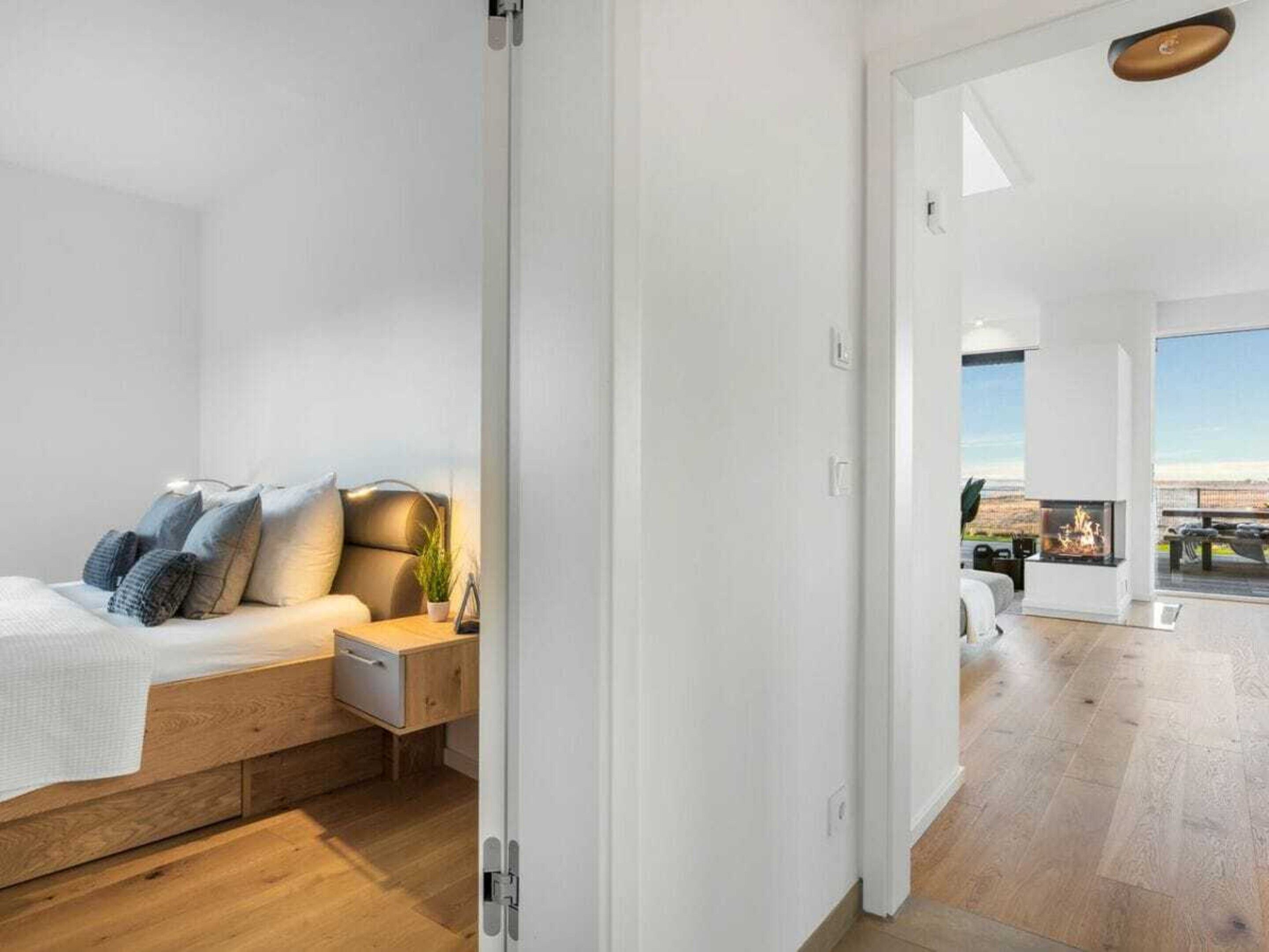 Et moderne soveværelse med en træseng, et natbord og udsigt til en balkon med pejs.