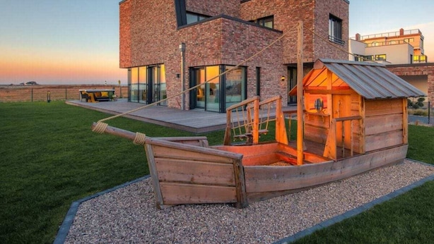 Ein modernes, zweistöckiges Haus mit Backsteinfassade und großen Fenstern.
