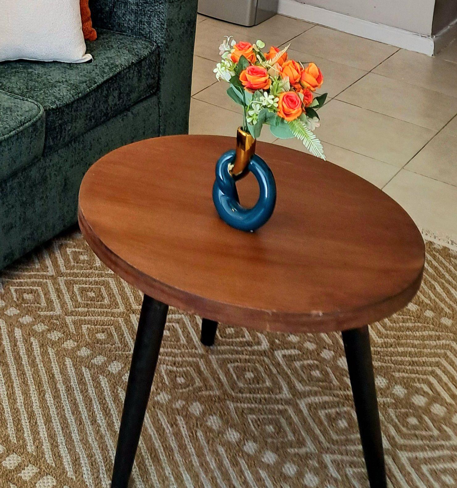 Un tavolo rotondo in legno con base ad anello blu, su un tappeto decorato.
