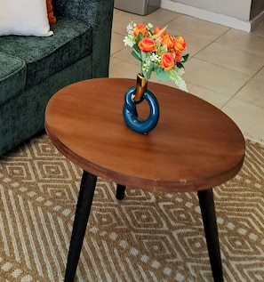 Un tavolo rotondo in legno con base ad anello blu, su un tappeto decorato.