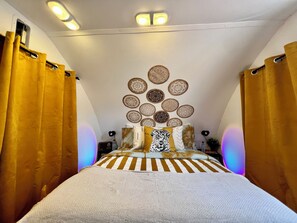 Une chambre à coucher avec un lit, des rideaux, des éléments de décoration murale et des luminaires au plafond.