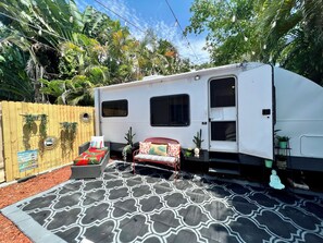 A white RV with a covered patio area, a red and white sofa, and a patterned rug. - Cozy 1-bedroom mobile home in soothing Miami with AC (Miami)