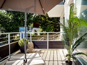 Eine Holzterrasse mit Metallgeländer, einem Blumentopf und einem Schild für einen Wellness-Resort.