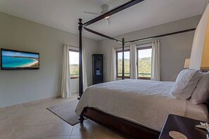 A bedroom with a four-poster bed, a television on the wall, and a view of the outdoors. - LUXURY WATERFRONT PENTHOUSE PRIVATE POOL 3 BEDROOM 3 BATHROOM (Lowlands)