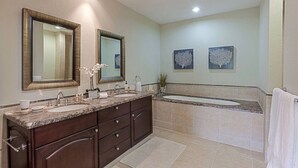 Une salle de bain moderne avec un meuble-lavabo à deux vasques, de grands miroirs et deux œuvres d’art accrochées au mur.