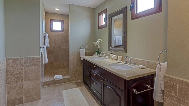Une salle de bain avec deux lavabos, un grand miroir et un espace douche.