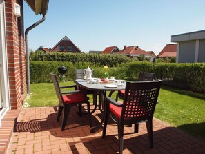 An outdoor patio with a table and chairs, a grill, and a well-maintained hedge. - Holiday Home in Wittmund With Swimming Pool (Wittmund)