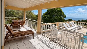 Ett takförsett utomhusområde med en pool, solstolar och en matgrupp.