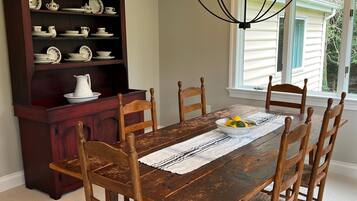 A dining room with a wooden table, chairs, a chandelier, and a china cabinet.