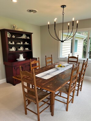 A dining room with a wooden table, chairs, a chandelier, and a china cabinet. - Eastern Shore Waterfront Retreat. Easy Access to Easton and St Michaels. (Denton)