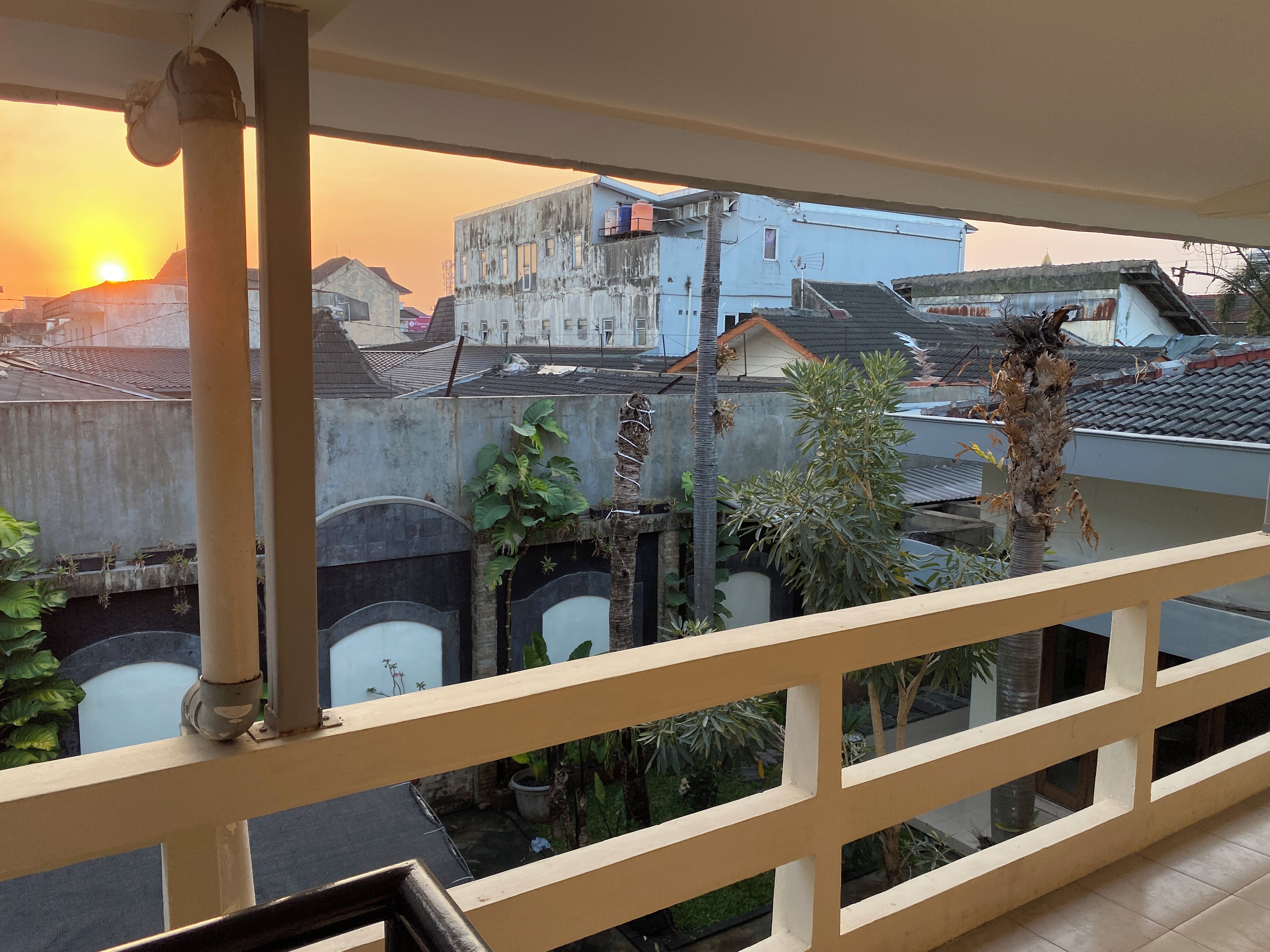 A balcony with a view of buildings and a sunset.