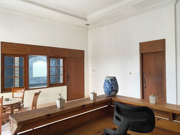 A room with a wooden bench, a large vase, and a window with wooden shutters.