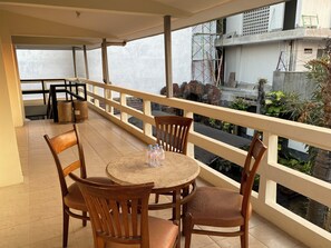 A balcony with a round table and chairs, a railing, and a view of a building with scaffolding.