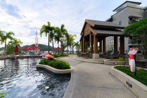 A pool area with lounge chairs and a gazebo, surrounded by palm trees and a modern building. - Surin - Freshly Renovated Stay (Thalang District)