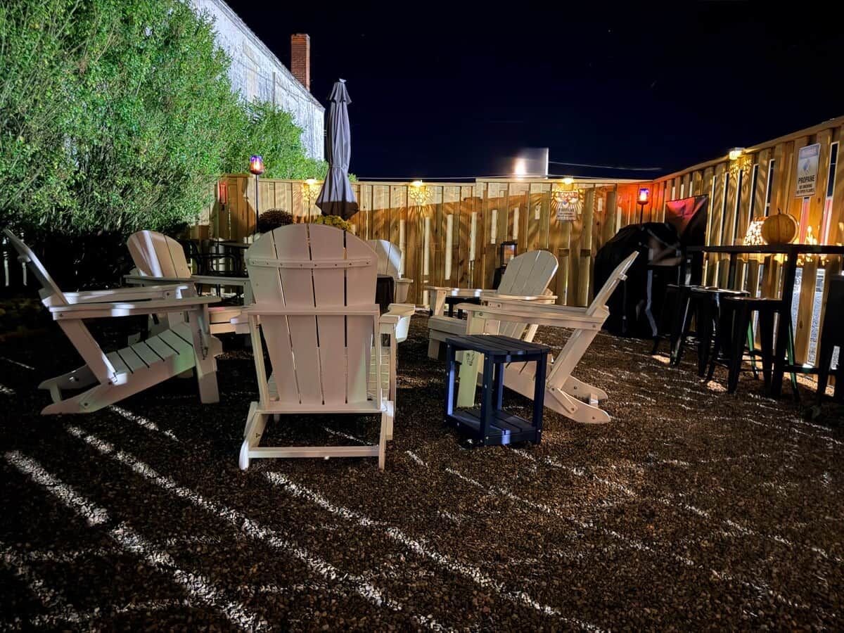 An outdoor seating area with wooden chairs and tables, a small table, and a decorative pumpkin.