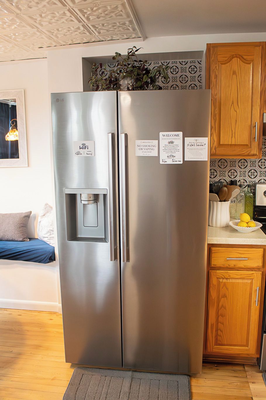 A stainless steel refrigerator with a water dispenser, a wooden cabinet, and a kitchen counter with a bowl of lemons.
