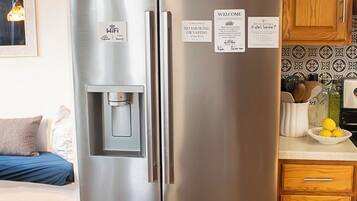 A stainless steel refrigerator with a water dispenser, a wooden cabinet, and a kitchen counter with a bowl of lemons.